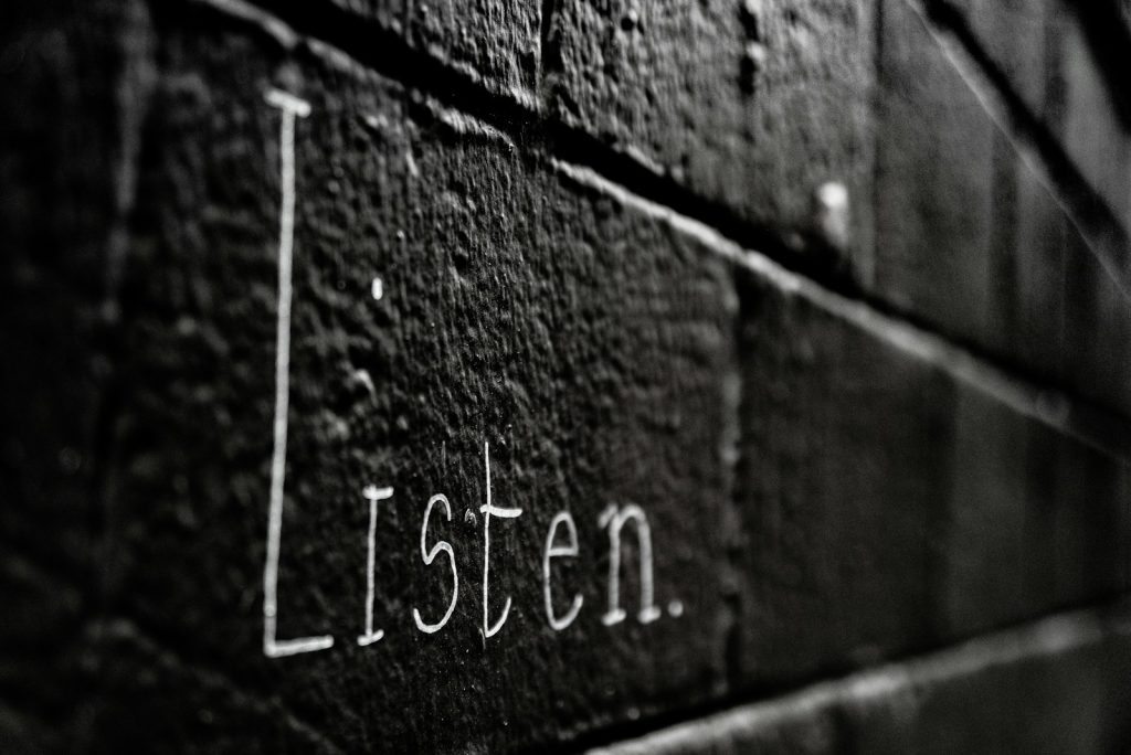 a black and white photo of the word listen written on a brick wall